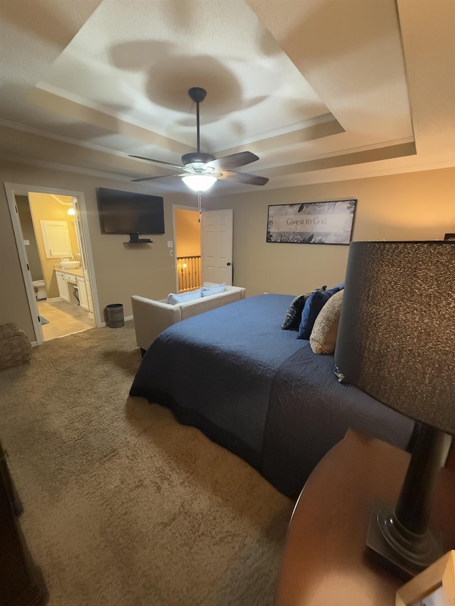 bedroom with ensuite bathroom, ceiling fan, a raised ceiling, and light colored carpet