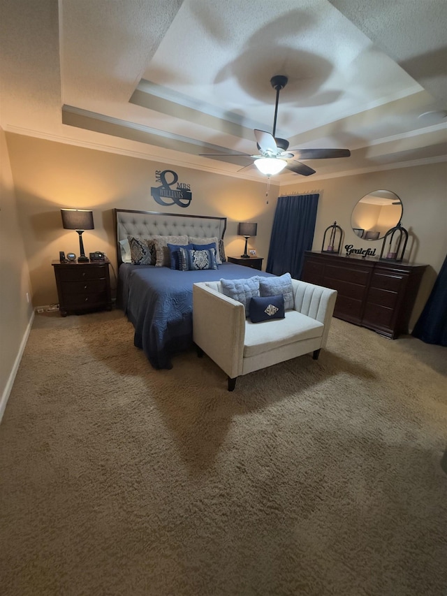 carpeted bedroom with ceiling fan, baseboards, and a raised ceiling