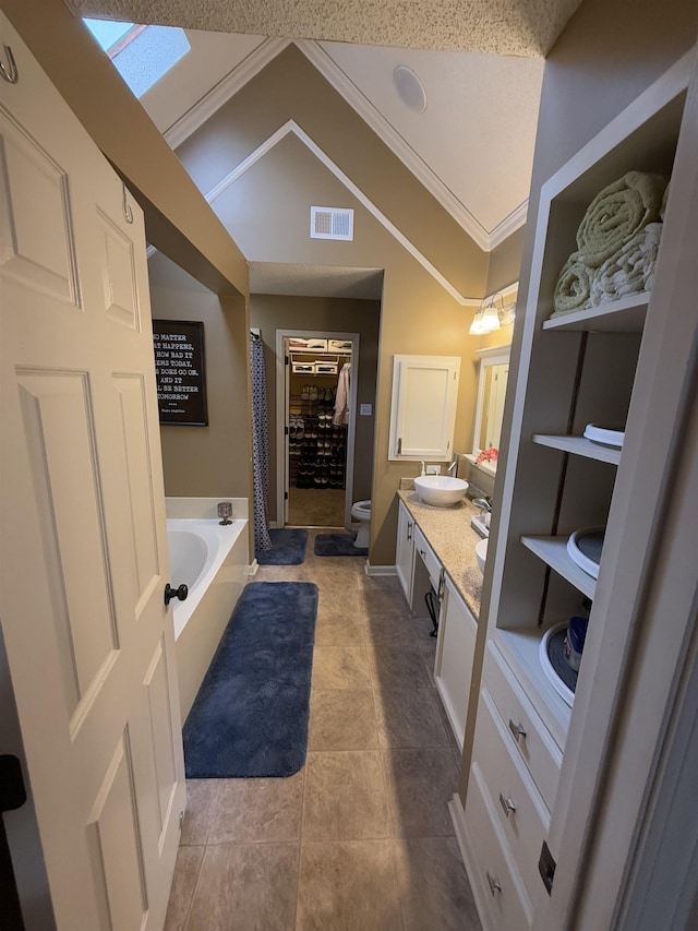 bathroom featuring a garden tub, toilet, visible vents, vanity, and vaulted ceiling