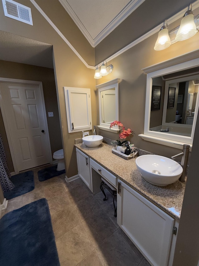 bathroom with double vanity, crown molding, visible vents, and a sink