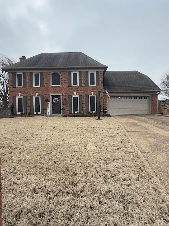 colonial house featuring a garage, brick siding, a shingled roof, driveway, and a chimney