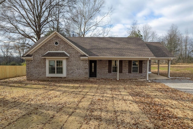 ranch-style home with brick siding, roof with shingles, and fence