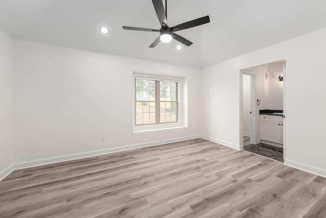 spare room with vaulted ceiling, recessed lighting, light wood-type flooring, and baseboards