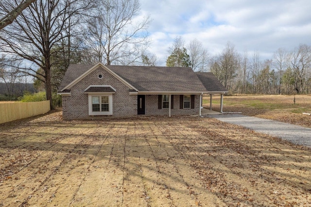 view of front facade with roof with shingles, fence, a porch, and brick siding