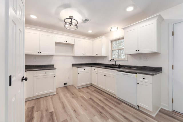 kitchen with white dishwasher, a sink, and white cabinets