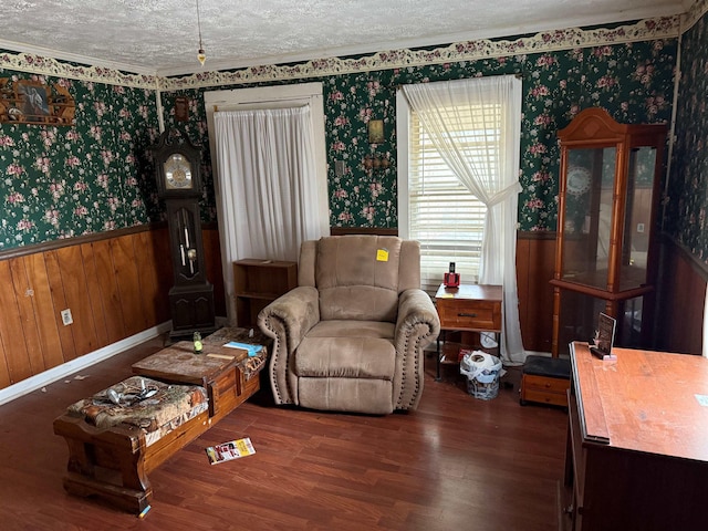 living area featuring wallpapered walls, wood finished floors, a textured ceiling, and wainscoting