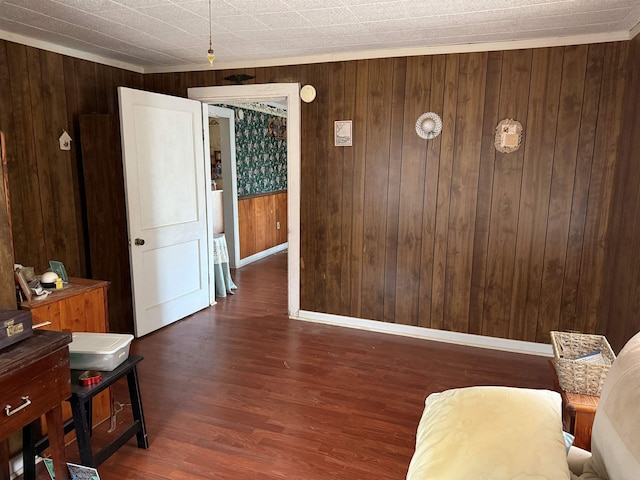 dining space featuring dark wood-style floors, wood walls, and baseboards