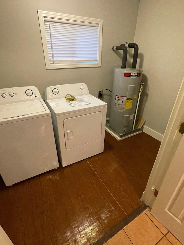 laundry room featuring electric water heater, laundry area, dark wood-type flooring, baseboards, and independent washer and dryer