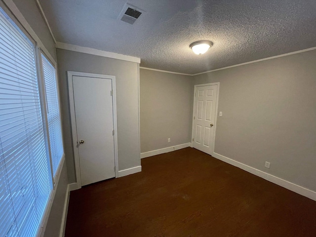 spare room featuring visible vents, crown molding, a textured ceiling, and baseboards