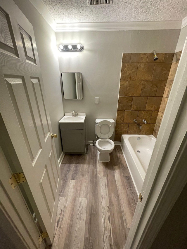 bathroom featuring visible vents, wood finished floors, a textured ceiling, vanity, and washtub / shower combination