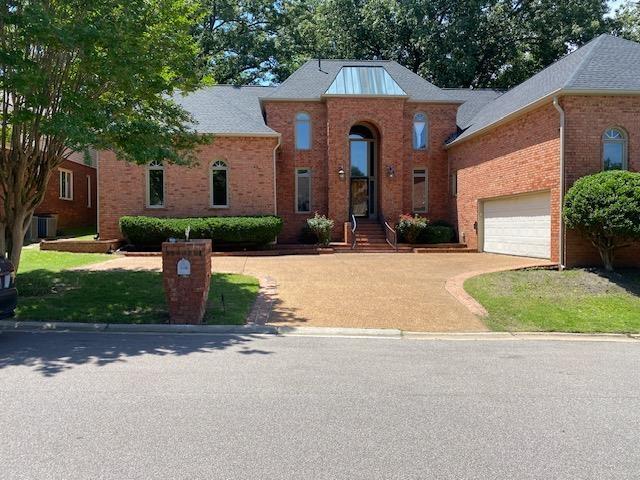 view of front facade featuring central AC unit, concrete driveway, and brick siding