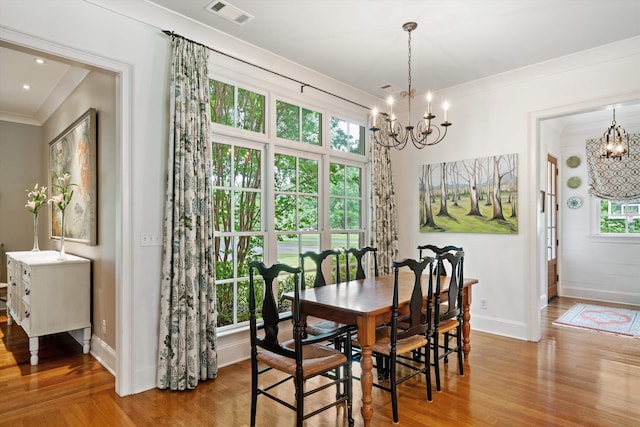 dining room featuring wood finished floors, visible vents, baseboards, an inviting chandelier, and crown molding