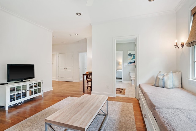 bedroom with ornamental molding, light wood-style flooring, and baseboards