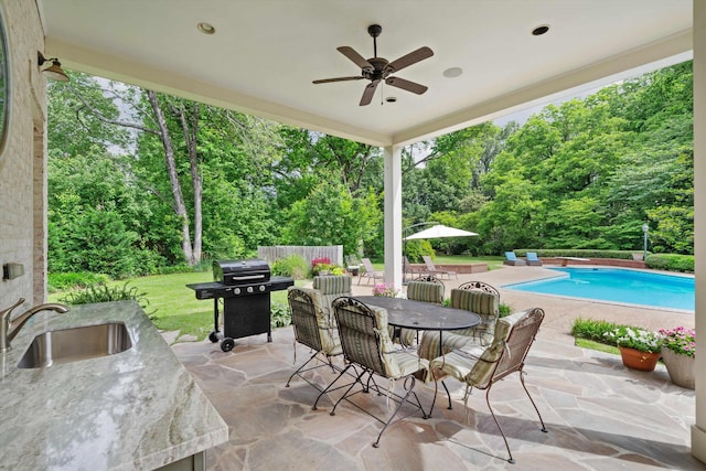 view of patio / terrace featuring an outdoor pool, area for grilling, ceiling fan, outdoor dining area, and a sink