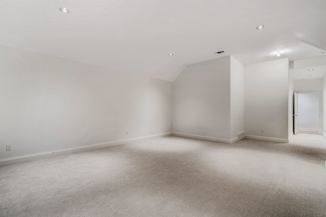 additional living space with light carpet, baseboards, visible vents, vaulted ceiling, and recessed lighting