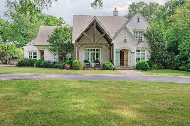 view of front of home featuring a front yard, brick siding, and a chimney