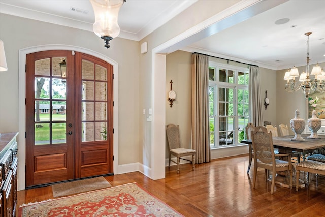 entrance foyer featuring an inviting chandelier, crown molding, wood finished floors, and french doors