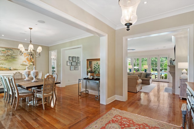 dining room featuring french doors, ornamental molding, wood finished floors, a chandelier, and baseboards