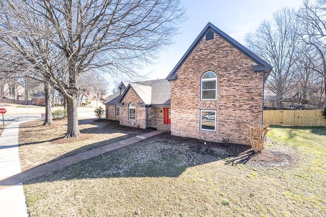 exterior space featuring a front yard, brick siding, fence, and roof with shingles