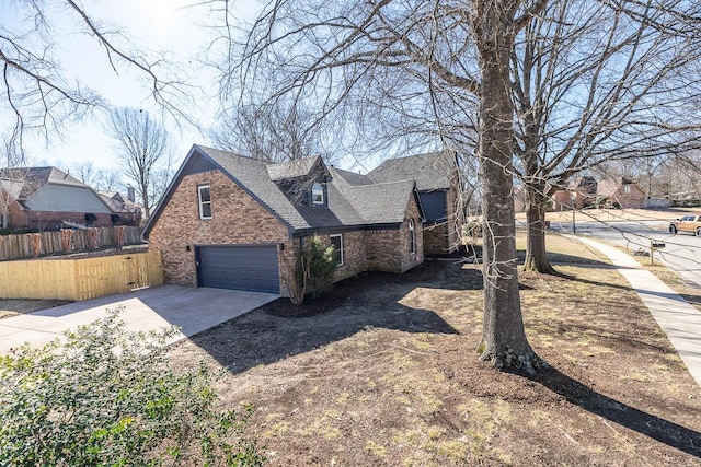 view of front of home with a garage, a shingled roof, concrete driveway, fence, and brick siding