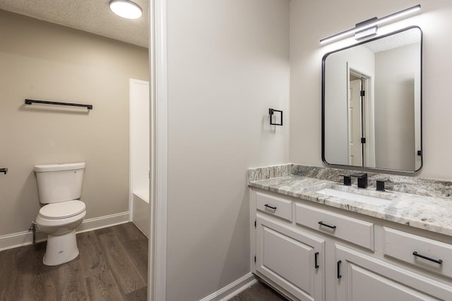 full bathroom with a washtub, toilet, wood finished floors, vanity, and baseboards