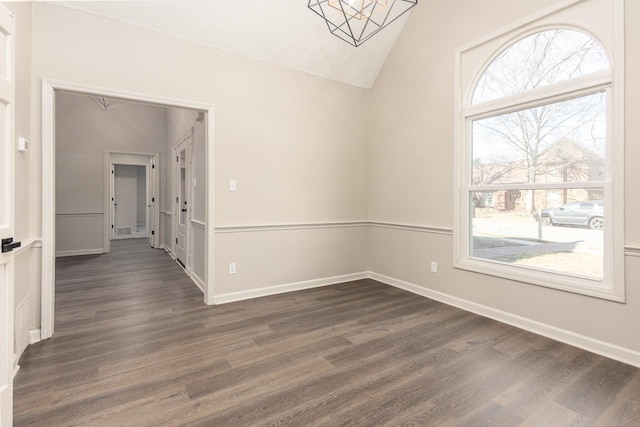 spare room with dark wood-style floors, visible vents, baseboards, and vaulted ceiling