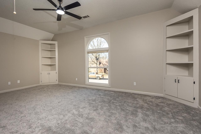 unfurnished bedroom featuring lofted ceiling, a textured ceiling, visible vents, baseboards, and carpet