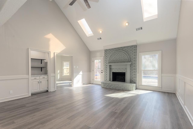 unfurnished living room featuring a brick fireplace, visible vents, a wealth of natural light, and wood finished floors