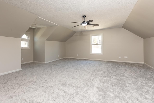 bonus room with plenty of natural light, a ceiling fan, vaulted ceiling, and a textured ceiling