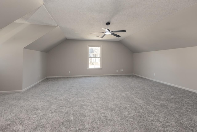 bonus room featuring baseboards, a ceiling fan, lofted ceiling, a textured ceiling, and carpet floors