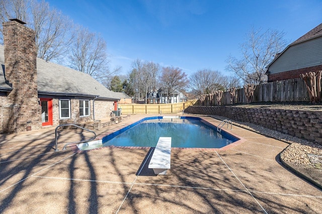 view of pool with a fenced in pool, a fenced backyard, a patio, and a diving board