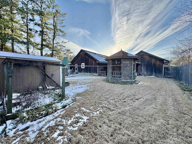 snow covered house featuring fence and a gazebo