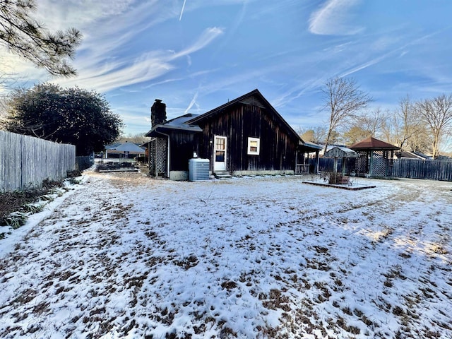 snow covered property with fence, a chimney, and a gazebo