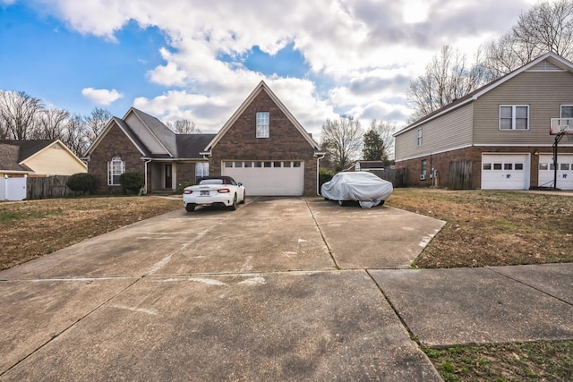 view of side of home with a garage, concrete driveway, brick siding, and fence