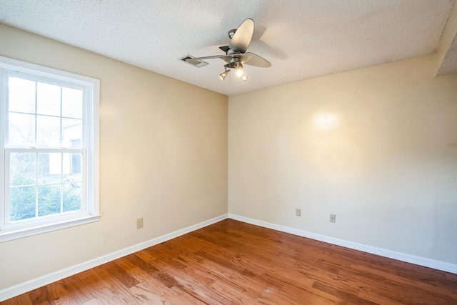 unfurnished room featuring ceiling fan, visible vents, a wealth of natural light, and wood finished floors