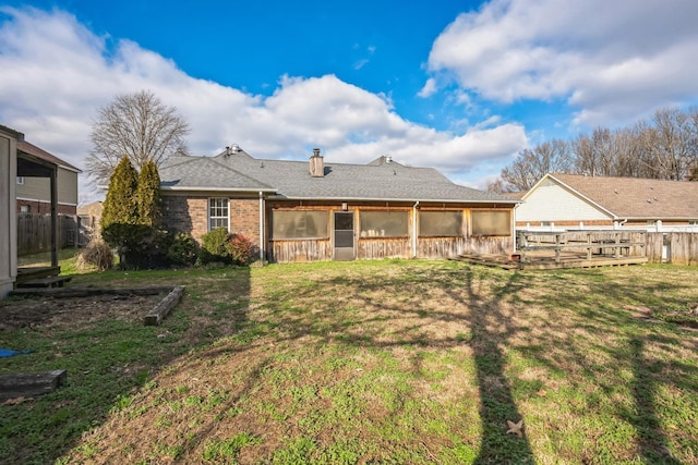 back of house with brick siding, a lawn, fence, and a sunroom