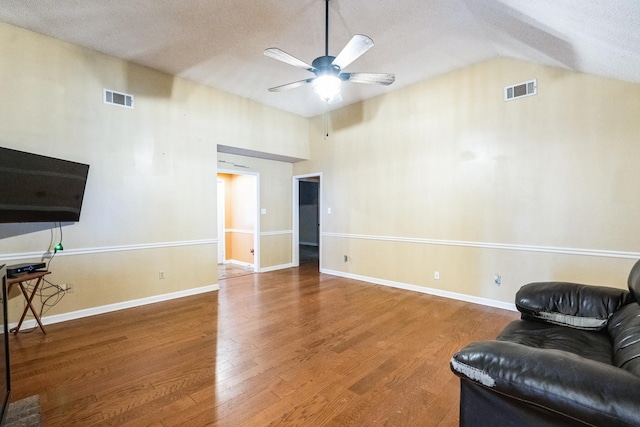 living room featuring lofted ceiling, wood finished floors, visible vents, and baseboards