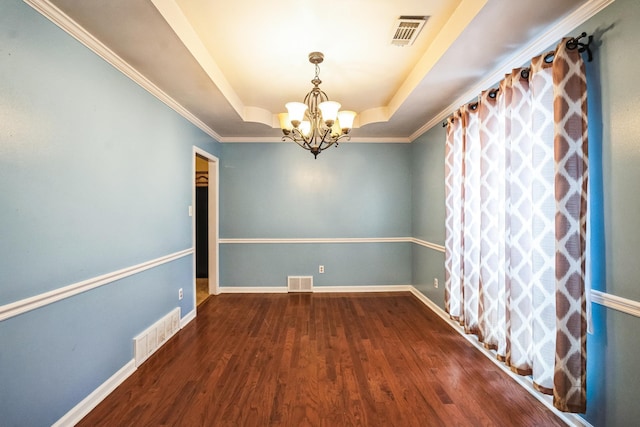 empty room with a raised ceiling, visible vents, and wood finished floors