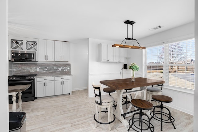 dining room featuring light wood-style flooring, visible vents, and baseboards