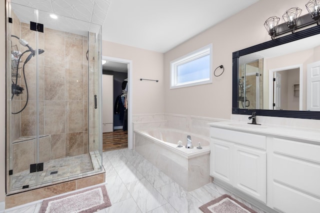 bathroom with a spacious closet, a shower stall, vanity, and a bath