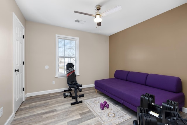 exercise room featuring light wood-type flooring, visible vents, ceiling fan, and baseboards