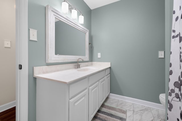 bathroom featuring marble finish floor, toilet, vanity, and baseboards