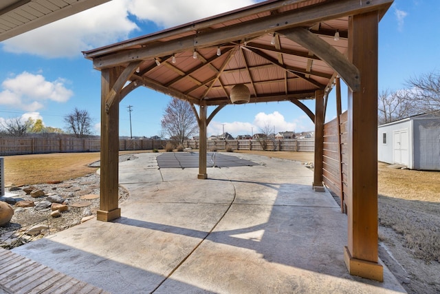 view of patio / terrace with a fenced backyard, an outdoor structure, a gazebo, and a shed