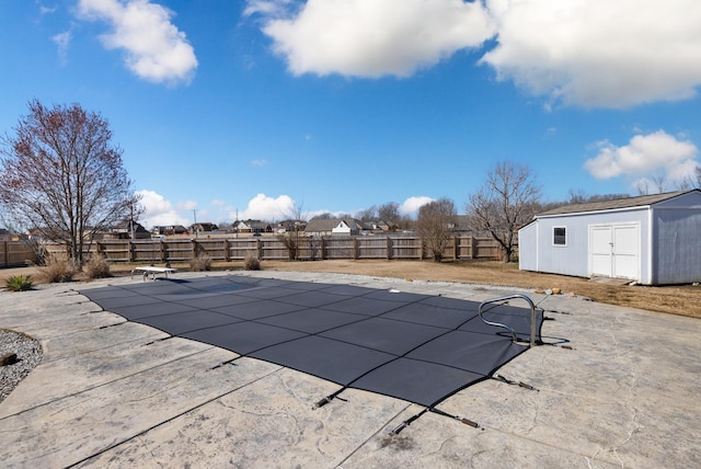 view of swimming pool featuring a storage shed, a fenced backyard, a fenced in pool, and an outdoor structure