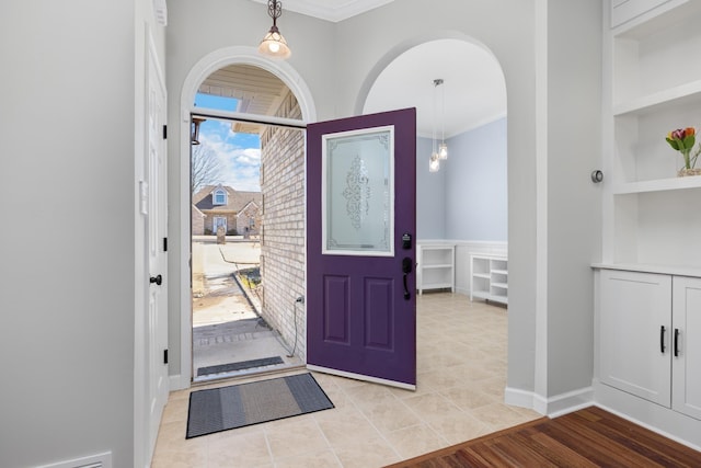 foyer entrance with baseboards and crown molding