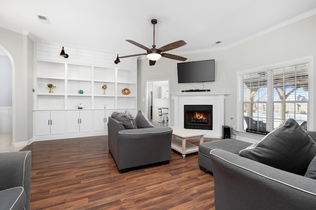 living area with arched walkways, ornamental molding, dark wood finished floors, and visible vents