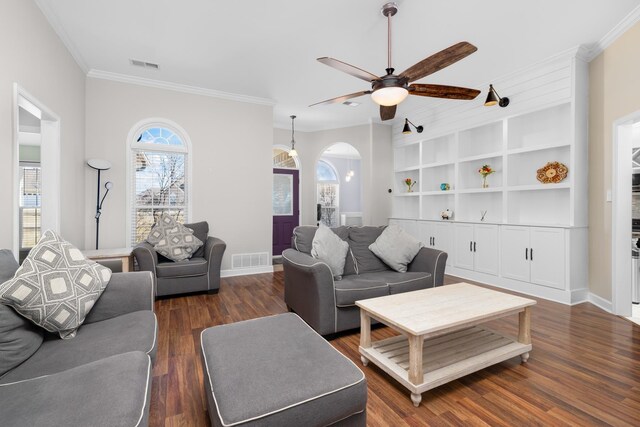 living area featuring arched walkways, dark wood-type flooring, visible vents, and crown molding