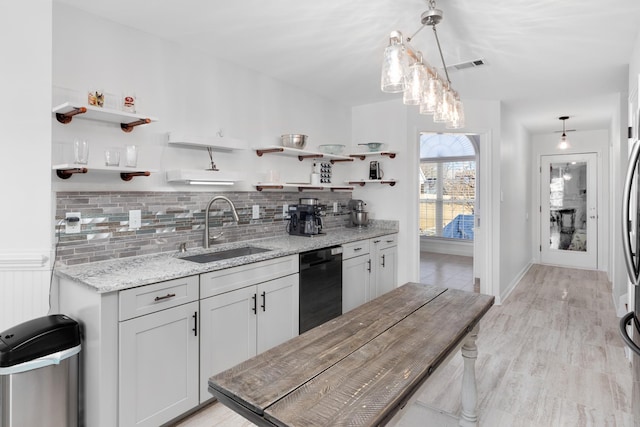 kitchen with black dishwasher, open shelves, hanging light fixtures, and a sink