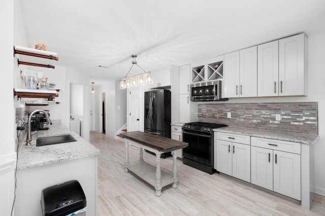 kitchen with black fridge, white cabinets, a sink, and range with gas cooktop