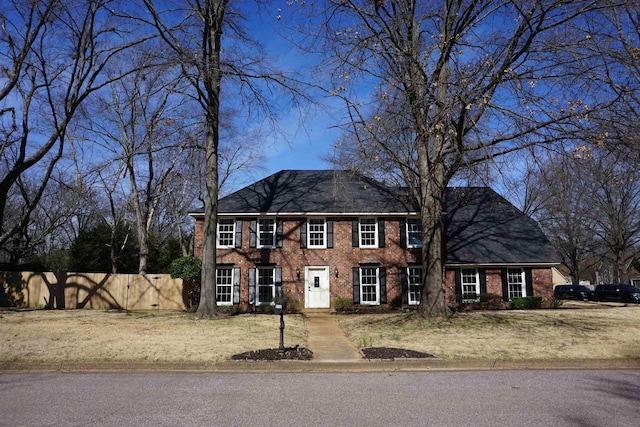 colonial-style house featuring brick siding and fence